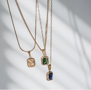 Dettaglio di pietre preziose smeraldo, blu e champagne su catene placcate in oro 18K