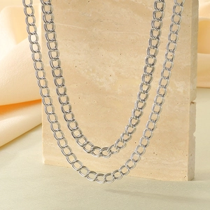 Double-layered silver stainless steel curb chain necklace on a textured stone stand