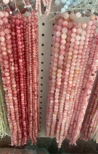 Multiple sizes of pink Persian jade and strawberry quartz beads hanging for DIY jewelry