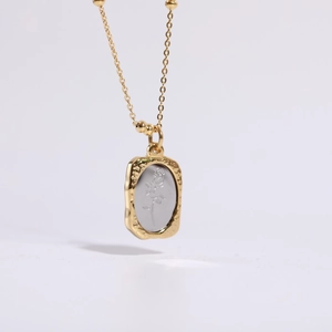 Detailed view of vintage gold necklace featuring an engraved silver rose pendant