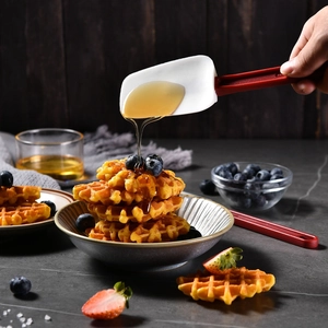 Kitchen silicone spatula set with red long handle used for drizzling honey on waffles
