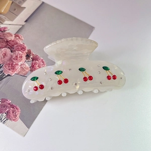 Close-up of acetic acid hair claw clip with cherry pattern and colorful rhinestones