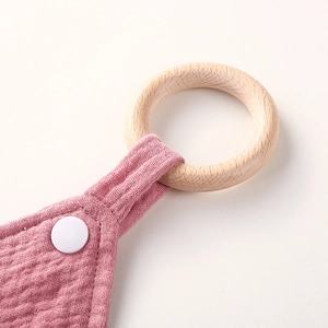 Detail of pink cotton gauze baby comforter featuring a natural wooden ring and snap fastener