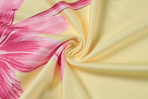 Detail of pink floral print on yellow twill fabric with soft texture and drape
