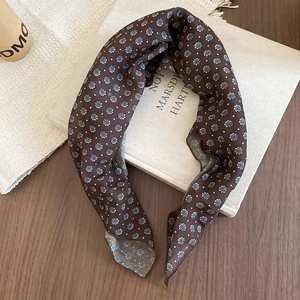 Close-up of a dark brown floral silk scarf on a vintage book with retro french style