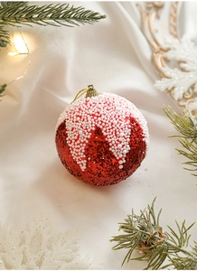 Détail d'une boule de Noël en mousse à paillettes rouge et blanc avec décor de pin festif