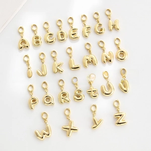 Macro shot of 26 golden 3D bubble letter charms with lobster clasps for DIY jewelry