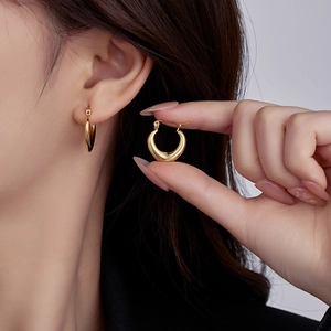 Detail view of 18K gold plated stainless steel hoop earrings worn by a female model