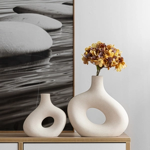 Set of two creative beige hollow ceramic vases with hydrangeas in a minimalist interior