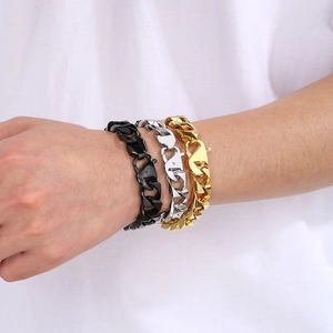 Close-up of stacked men's Cuban link bracelets in black, silver and golden stainless steel