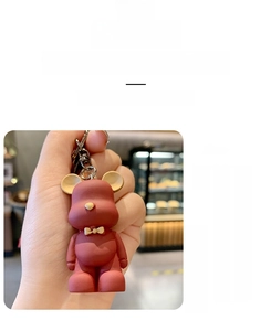 Macro view of matte burgundy resin bear keychain featuring a golden metallic bow detail