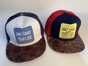 Detail of two snapback hats featuring vintage brown leather brims and letter prints