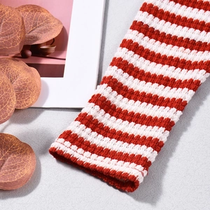 Detail of red and white striped knit fabric with fine needlework and rustic props