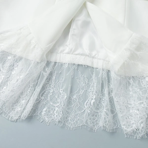 Detail view of white blazer hem featuring delicate floral eyelash lace and satin lining