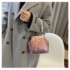 Pink metallic crossbody bag with pearl handle and butterfly clasp shown with model