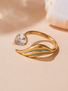 Detail of adjustable gold ring featuring pear-cut zircon and teal enamel wing decor