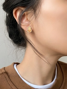Detail of gold-plated gourd stud earring with amber stone on model's ear