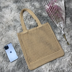 Detail of khaki crochet knit shoulder bag showing hollow pattern on plush surface