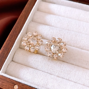 Macro view of 14K gold plated flower stud earrings with sparkling crystals in wood box