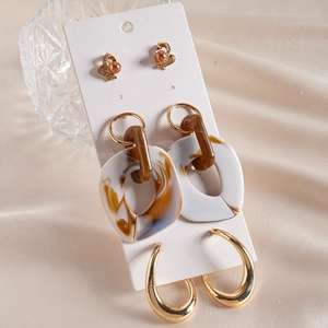 Detailed set of bow pearl studs and marble resin hoop earrings on display cards