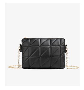 Detail of black quilted shoulder bag with triangular stitching and gold chain
