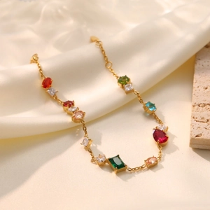 Elegante goldene Halskette mit bunten Zirkonia-Steinen auf weißem Seidenhintergrund