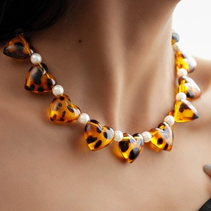 Detail of amber leopard print acrylic heart pendants and white pearls on the necklace