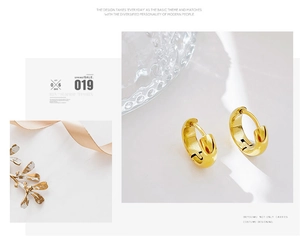 Detail of high-polish gold hoop earrings on elegant white marble with luxury decor