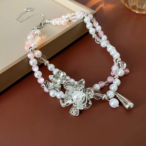 Macro detail of French style double-layer pearl necklace with silver flower and water drop charms