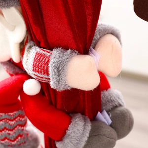 Close-up detail of a plush Santa Claus curtain buckle holding a luxury red velvet drape.