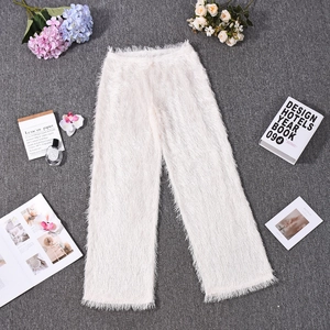 Détail du pantalon blanc en fausse fourrure avec texture frangée douce sur fond minimaliste