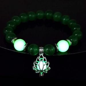 Close-up of luminous green beads and a glowing lotus pendant on a yoga bracelet