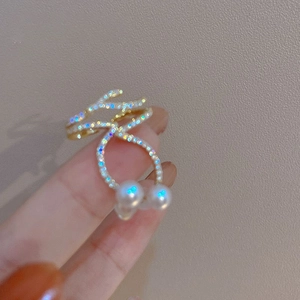 Macro shot of gold intertwined ring with sparkling zircons and two white pearls