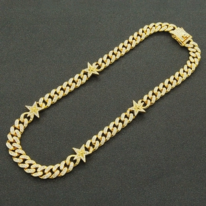 Macro shot of gold Cuban link chain necklace with iced out star pendants and zircon stones