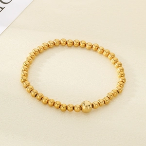 Close-up of minimalist 18K gold plated stainless steel bead bracelet on white texture