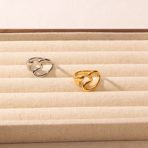 Close-up of gold and silver open heart rings on a beige velvet jewelry display tray