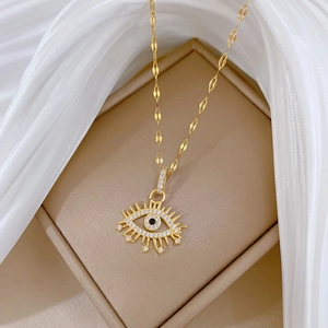 Gold evil eye necklace with zircon stones and flat chain on soft white fabric