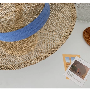 Detail view of khaki straw hat with elegant blue ribbon and fine handwoven texture