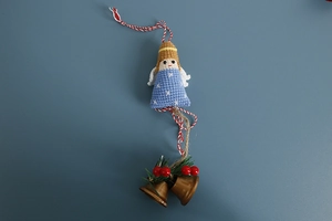 Detail of crochet angel ornament with blue yarn, golden bell and red berries for decoration