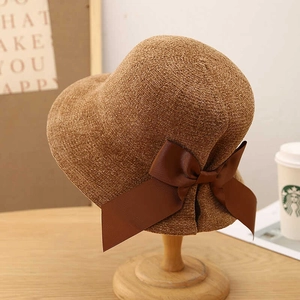 Elegant dark brown straw sun hat with a large satin bow on a wooden display stand