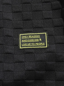 Detail of black waffle knit fabric texture with neon yellow embroidered quote label