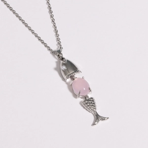 Detailed macro view of a silver fish pendant with pink gemstone and movable body segments