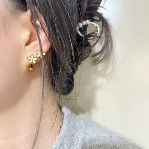 Elegant 3D gold-rimmed white flower stud earrings worn by a model in soft light