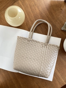 Detail of hand-woven straw tote bag showing clear mesh texture on a white album