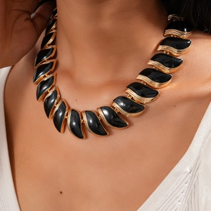 Gros plan d'un collier feuille noir vintage avec monture en métal doré sur femme
