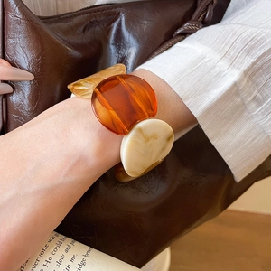 Detail of amber acrylic resin chunky link bracelet with marbled pattern on a female wrist