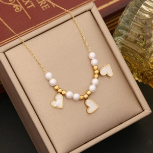 Elegant gold chain necklace with white pearl beads and heart pendants in a jewelry box