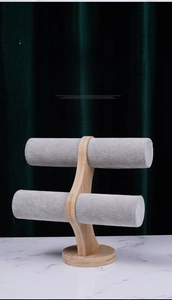 Close-up of dual-tier bamboo jewelry stand with grey velvet bars on marble