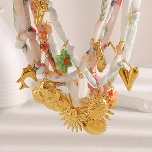 Dettaglio di una collana a strati con conchiglie dorate e perline floreali colorate