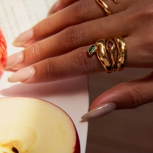 Detailed view of lava texture gold rings with emerald and ruby zircon inlays